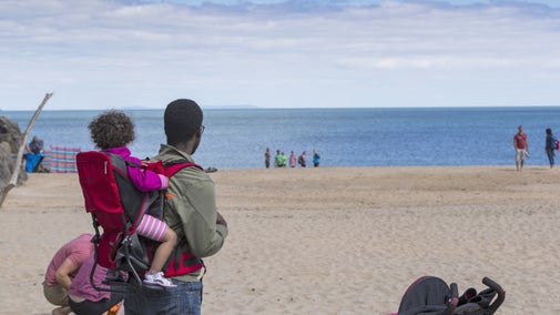Father with child in a child carrier on back looking out to see at Barafundle Bay, Stackpole, Pembrokeshire